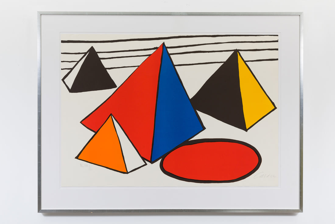 A framed print by Alexander Calder hung on a white wall. The piece shows four abstract pyramids in various colours of red, black, orange, blue and yellow. There are black stripes in the background and a red circle with a black outline in the foreground.